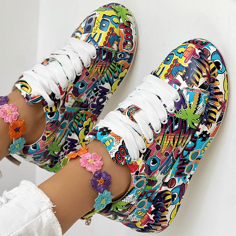 Colorful graffiti-print sneakers with white laces, worn with embroidered floral anklets on a white background.