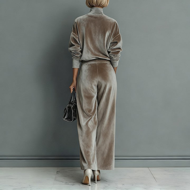 A person wearing a taupe, velour, high-neck long-sleeve top and matching wide-leg pants, paired with light heels.
