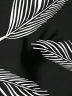 Close-up of black fabric with white, minimalist line-drawn palm leaf patterns.