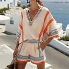 Beige two-piece resort set with orange and blue striped accents, V-neck embellished tunic, and elastic-waist shorts.