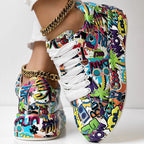 White lace-up sneakers featuring a vibrant, multicolored pop art graffiti print and gold chain ankle accessories.