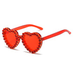 Red heart-shaped sunglasses with translucent frames and a rim of sparkling red rhinestones.