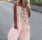 Woman wearing a loose-fitting pink jumpsuit with a watercolor floral print and button-strap details.