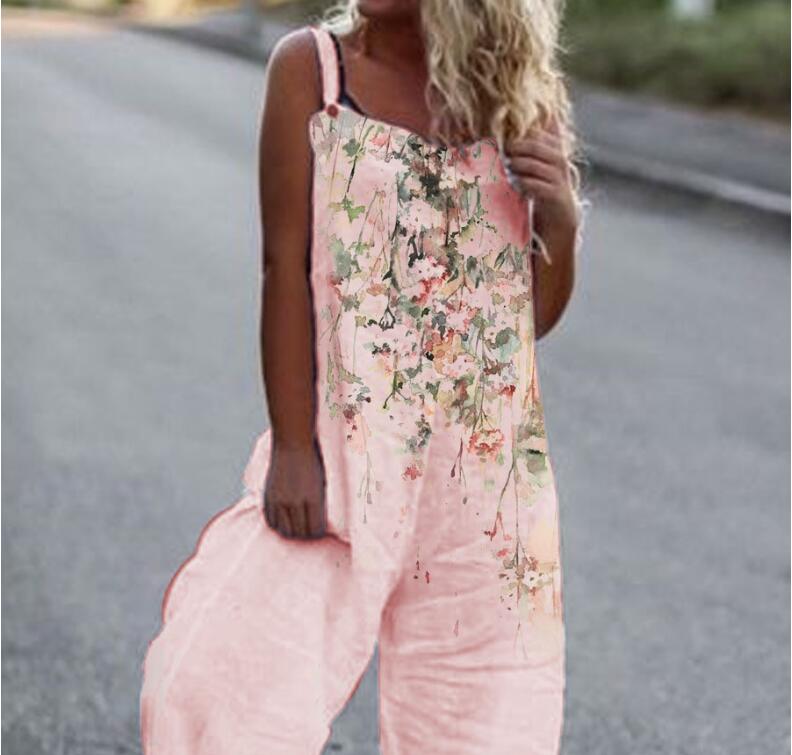 Woman wearing a loose-fitting pink jumpsuit with a watercolor floral print and button-strap details.