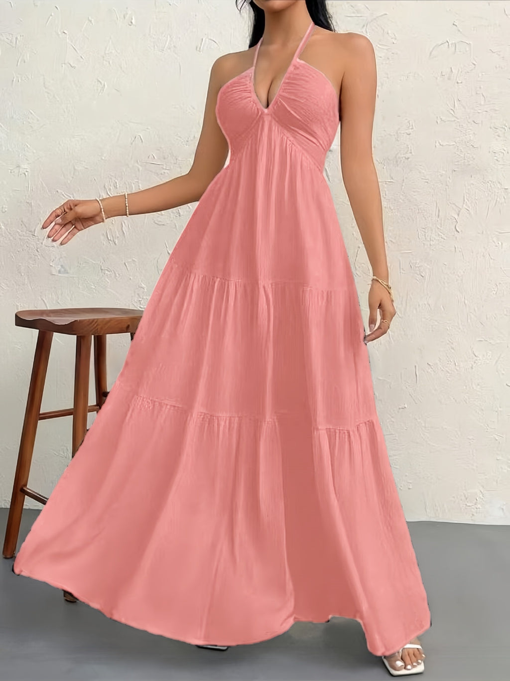 A dusty pink, sleeveless halter maxi dress with a gathered, tiered skirt and a textured, lightweight fabric.