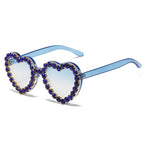 Heart-shaped sunglasses with light blue gradient lenses and blue frames, embellished with dark blue rhinestone borders.