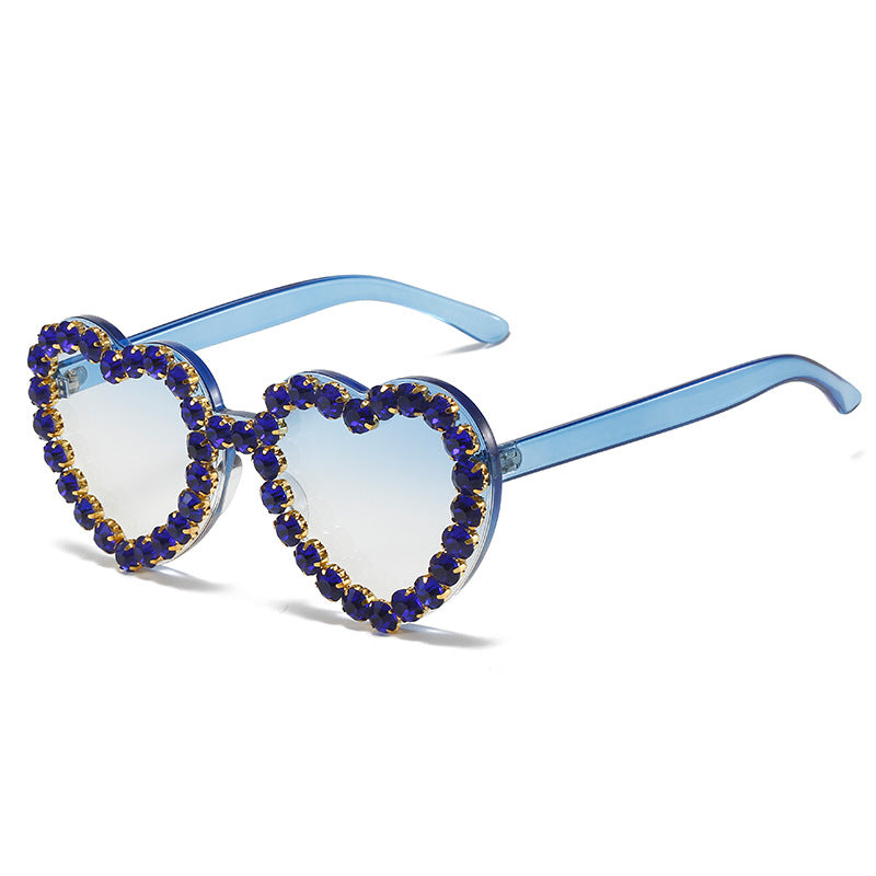 Heart-shaped sunglasses with light blue gradient lenses and blue frames, embellished with dark blue rhinestone borders.