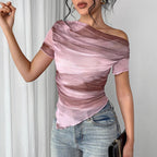 A woman wearing a pink and brown tie-dye sheer, asymmetric off-shoulder top with short sleeves and a raw hem.
