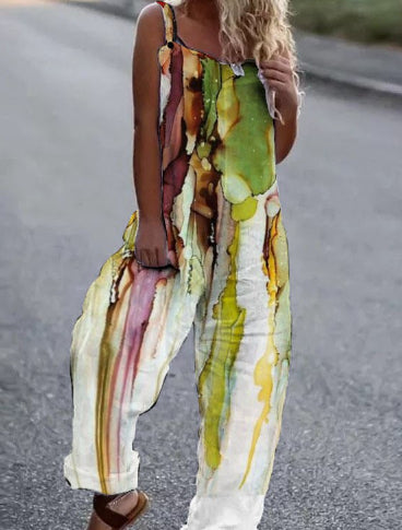 Woman wearing a sleeveless, wide-leg jumpsuit with an abstract, watercolor-style print in green, yellow, and brown.
