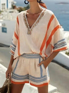 Beige two-piece set with orange and blue stripes, v-neckline, beaded trim, and relaxed-fit shorts.