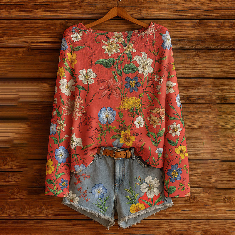 Red long-sleeve blouse with a vibrant floral print paired with denim shorts featuring a matching flower pattern.