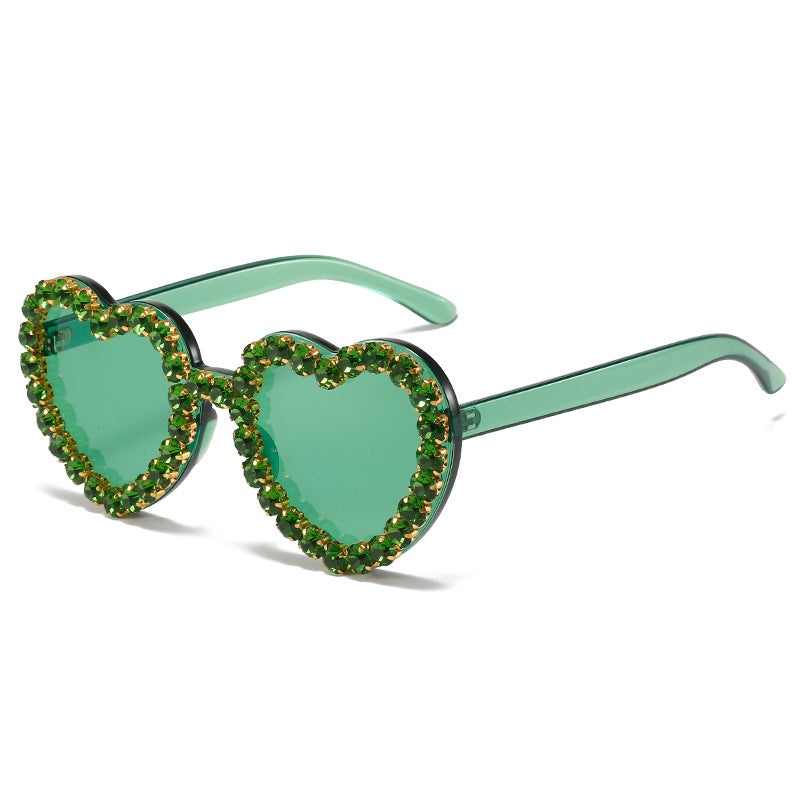 Heart-shaped green sunglasses with translucent frames and rims embellished with sparkling green crystals.