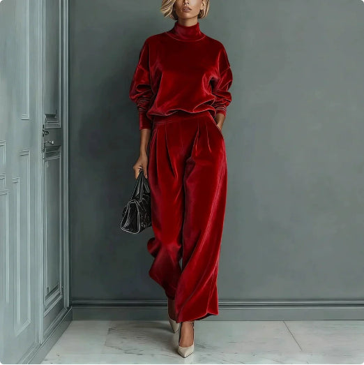 A woman wears a red velour set with a high-neck long-sleeve top and matching high-waisted wide-leg trousers.