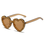 Heart-shaped sunglasses with translucent brown frames and a border of sparkling amber rhinestones.