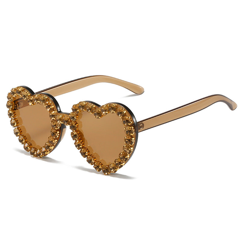 Heart-shaped sunglasses with translucent brown frames and a border of sparkling amber rhinestones.