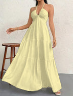 A soft yellow, textured tiered maxi dress with a halter neckline and ruched bodice.