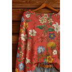 Red long-sleeve blouse with a vibrant, multi-colored floral botanical print and a subtle crinkled texture.