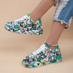 White sneakers with vibrant multi-colored graffiti print, chunky soles, and white laces, worn with ripped jeans.