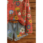 Red long-sleeve top with vibrant floral print and blue denim frayed-hem shorts with matching flower details.