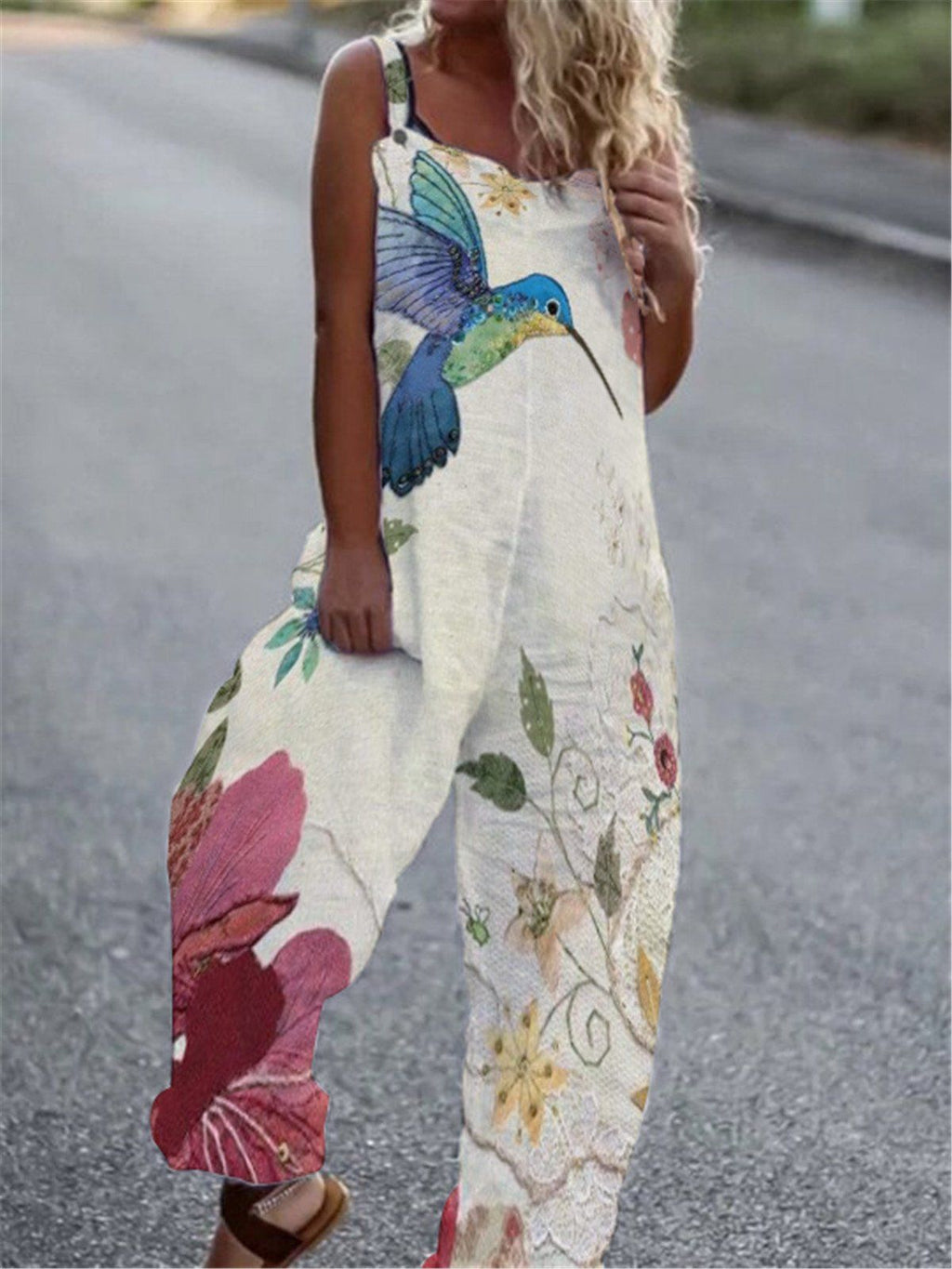 Cream-colored sleeveless jumpsuit with a large blue hummingbird and floral print in pink, yellow, and green.