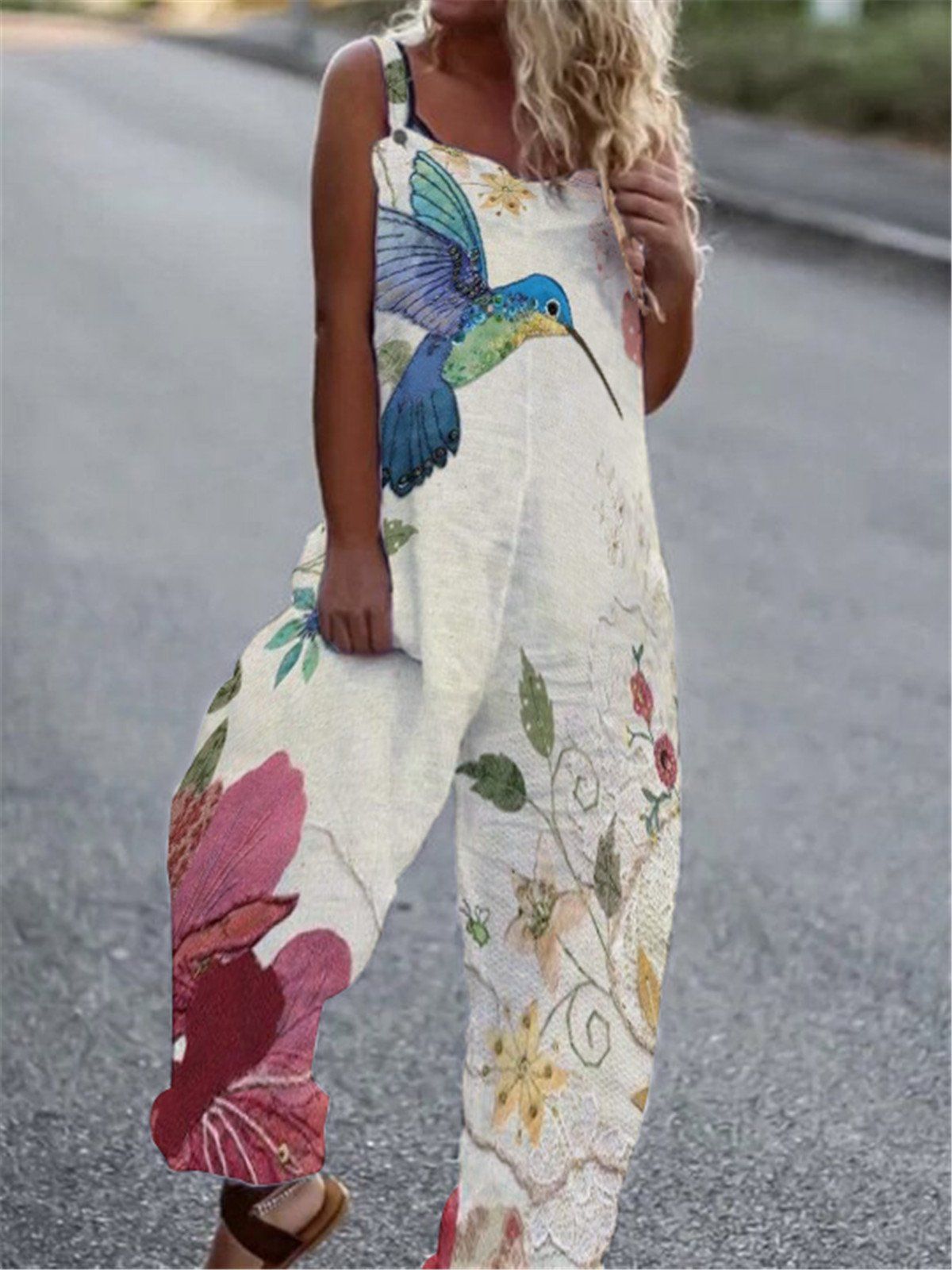 Cream-colored sleeveless jumpsuit with a large blue hummingbird and floral print in pink, yellow, and green.