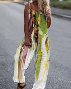 Woman wearing a loose-fitting, sleeveless jumpsuit with a colorful abstract watercolor print of green and burgundy.