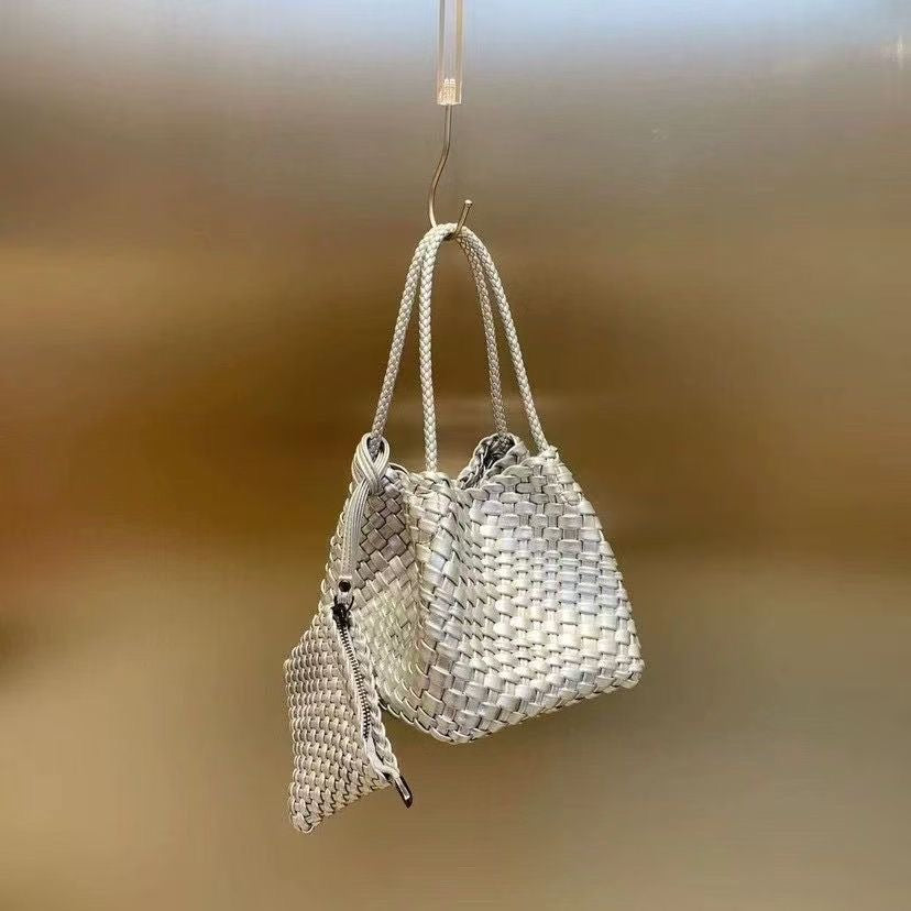 Metallic silver woven bucket bag with braided shoulder straps and a matching zip-up pouch attached.