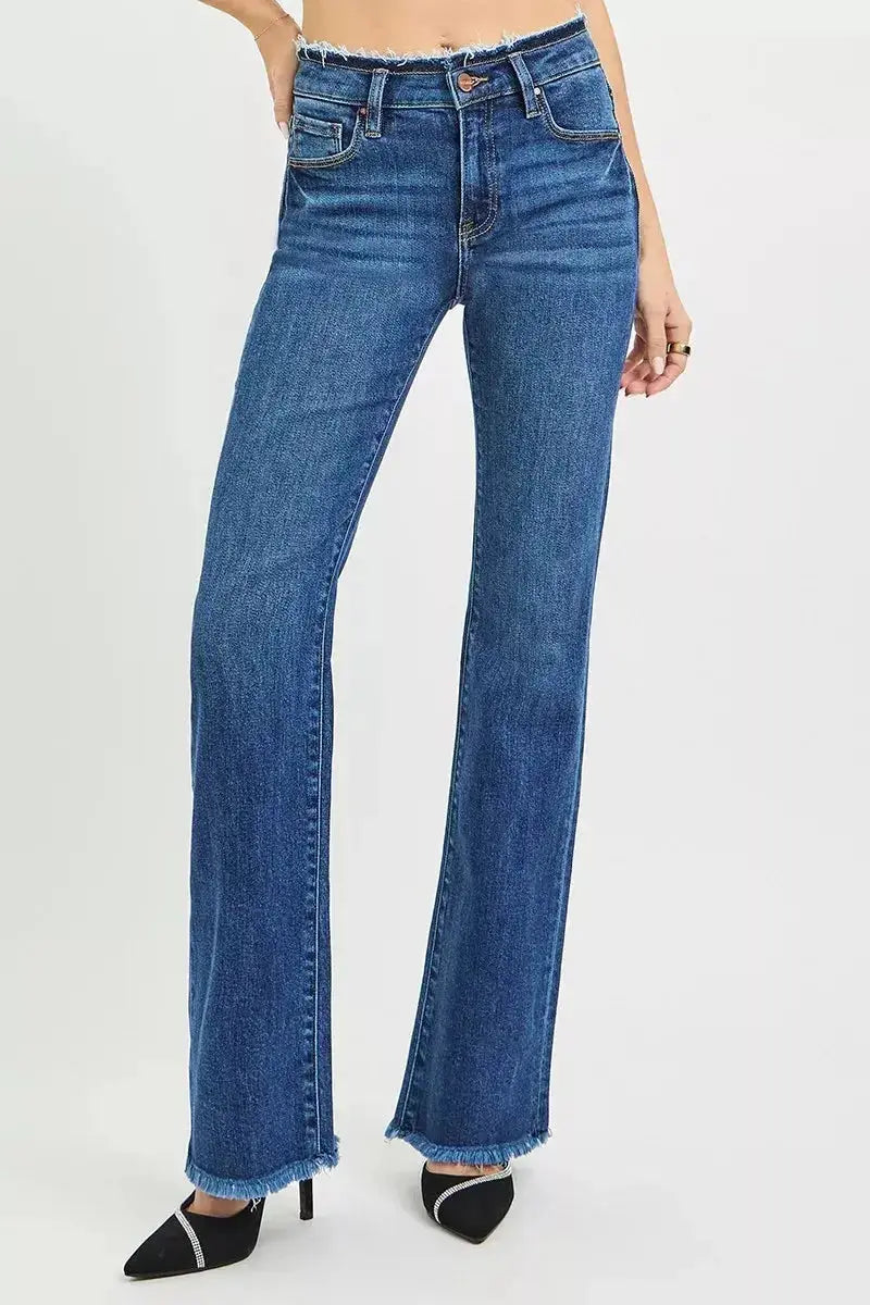 Mid-rise bootcut jeans with frayed waist and raw hem detail, shown in a natural denim wash, styled on a model.
