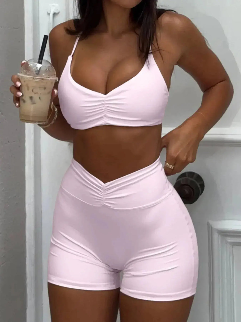 Women wearing a ruched sports bra and high-waisted shorts activewear set by Trendsi, perfect for workout and athleisure.