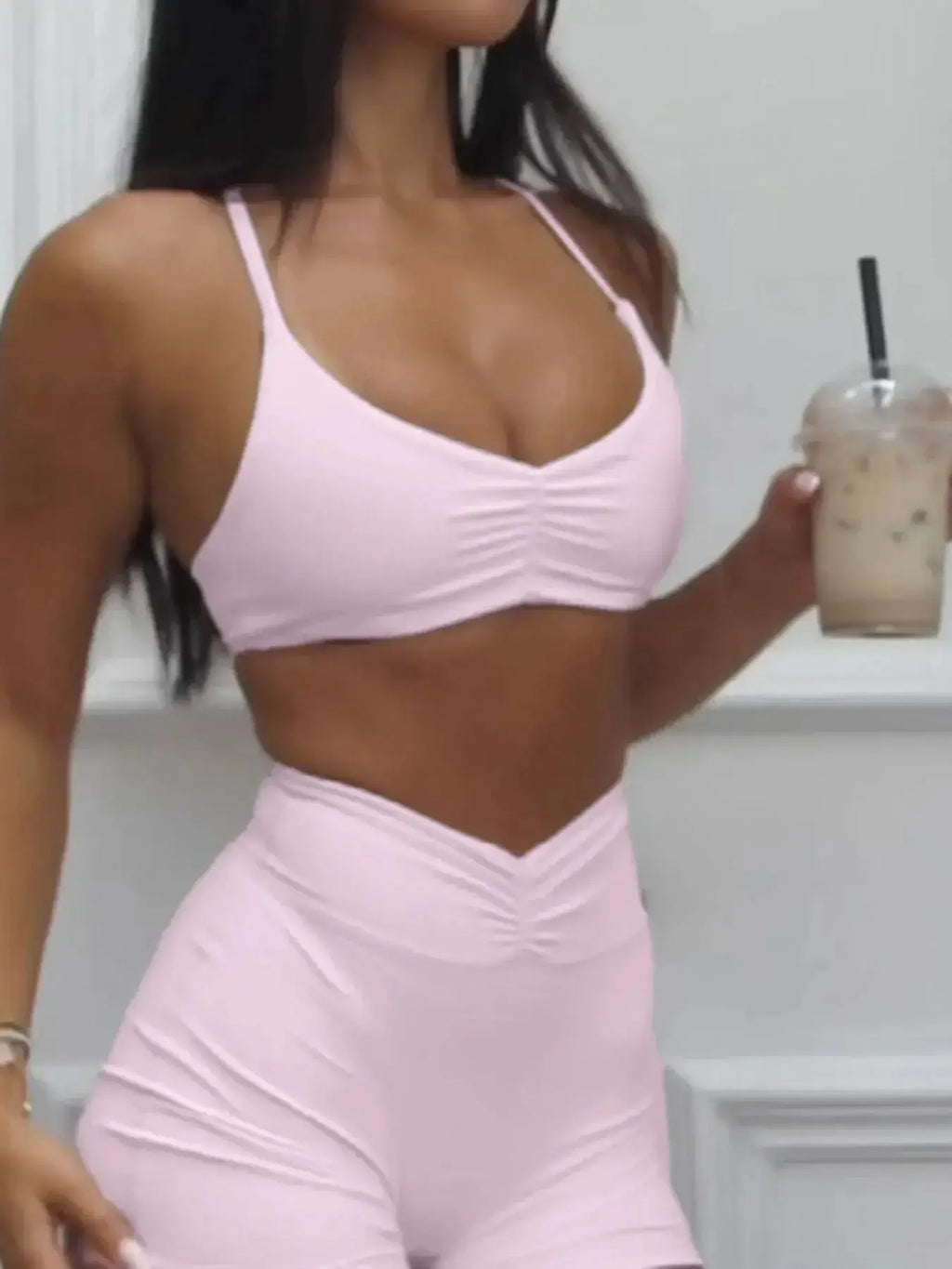 Women wearing a trendy ruched sports bra and high-waisted shorts matching activewear set by Trendsi, perfect for workouts.