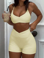 Women wearing a trendy ruched sports bra and high-waisted shorts matching activewear set by Trendsi, ideal for workouts and casual wear.