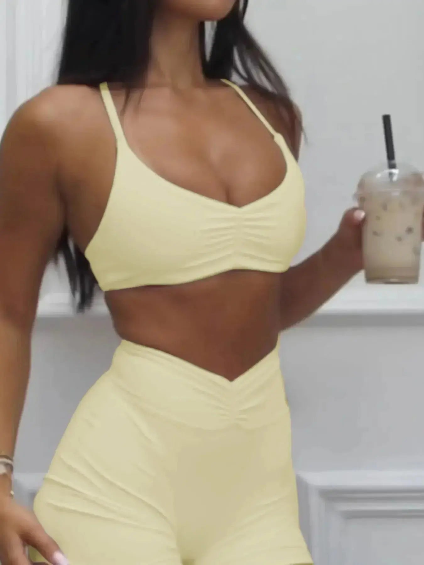 Women wearing a ruched sports bra and high-waisted shorts matching activewear set by Trendsi, designed for workout comfort.