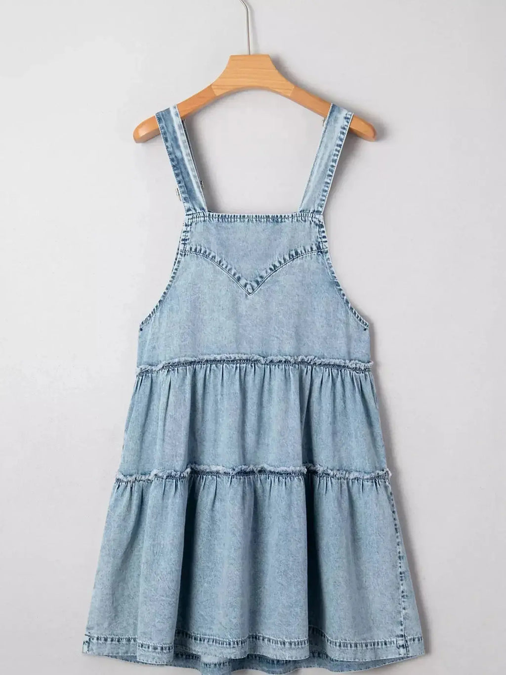 Women’s tiered flowy denim overall dress with raw hem, 100% cotton, by Trendsi, shown on a model in a casual outdoor setting.