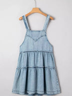 Women’s tiered flowy denim overall dress with raw hem, 100% cotton, by Trendsi, shown on a model in a casual outdoor setting.