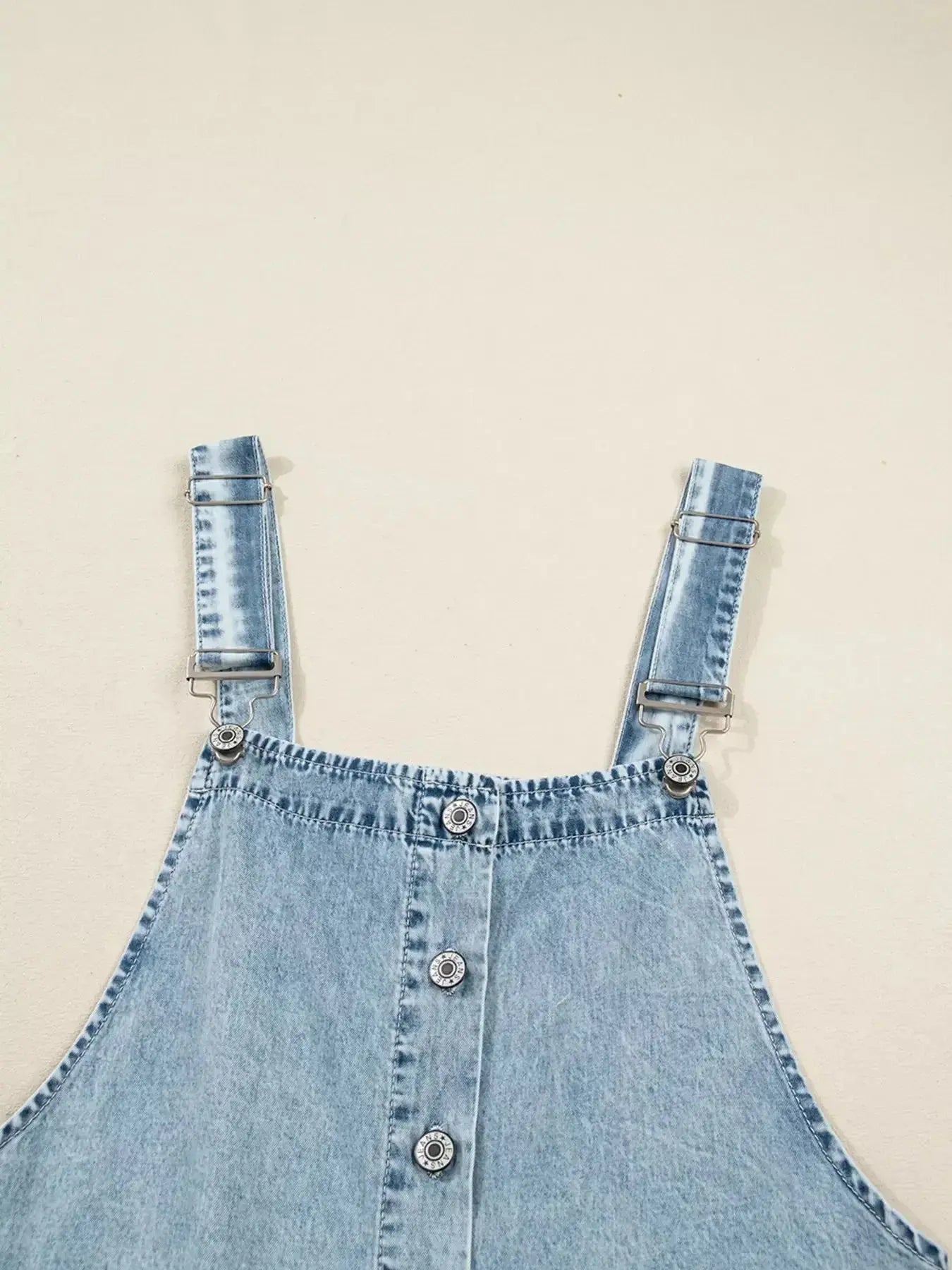 Women’s tiered flowy denim overall dress with raw hem, made of 100% cotton, by Trendsi, shown on a model.