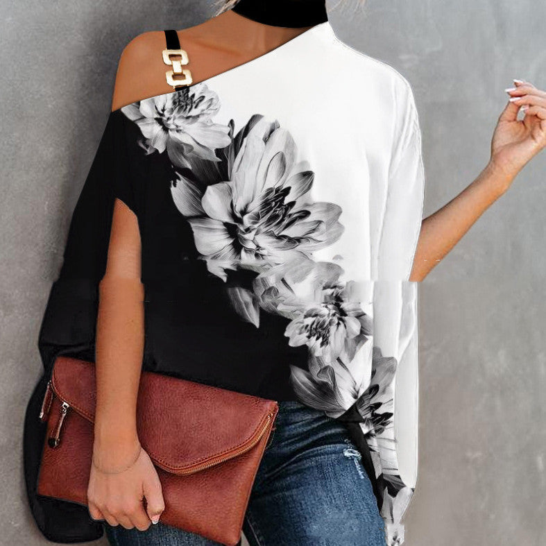 Black and white floral print asymmetrical blouse with a gold chain strap detail, paired with a brown clutch.