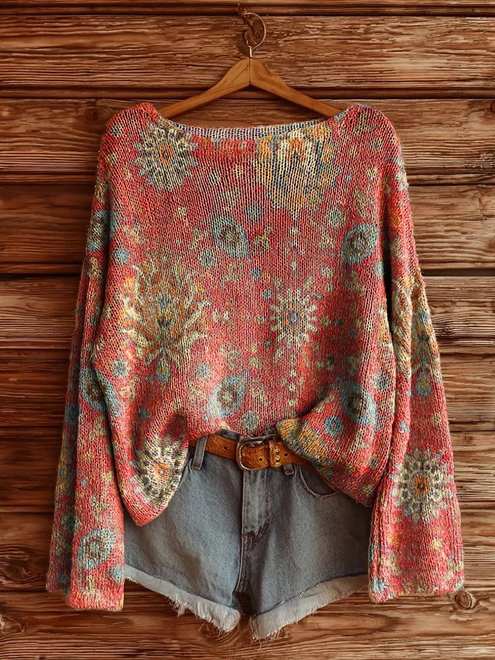 Coral knit sweater with a multicolored floral pattern, styled with denim shorts and a tan leather belt.
