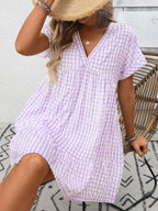 Lightweight plaid V-neck mini dress with ruffle hem, trendy seasonal fashion by Trendsi, shown on a model.