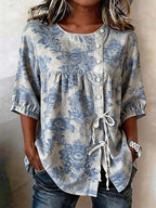 Blue and beige floral print loose-fit blouse with a button-down front, side tie detail, and short puff sleeves.