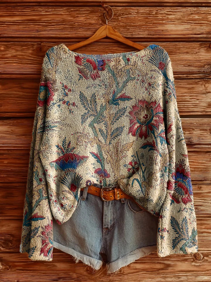 Cream-colored floral knit sweater with blue and red botanical pattern, styled with denim shorts and a leather belt.