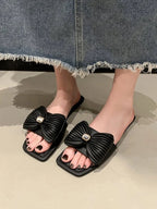 Women's black faux leather flat sandals with elegant bow-knot detail, stylish and comfortable for casual wear.