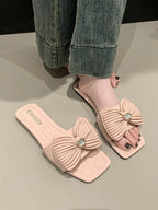 Women's elegant bow-knot faux leather flat sandals with open toes and ankle straps, designed by Trendsi.