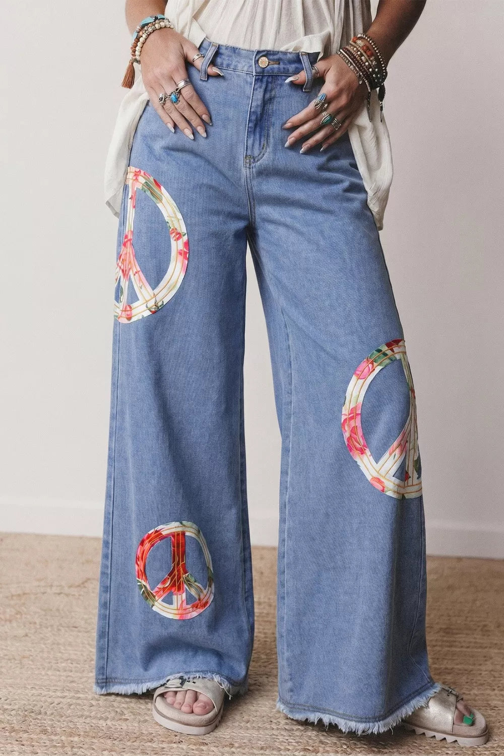 Floral peace sign wide leg jeans from Trendsi featuring a relaxed fit with floral and peace sign embroidered design.