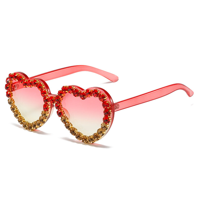 Heart-shaped sunglasses with pink-to-yellow gradient lenses and red and gold crystal embellishments.