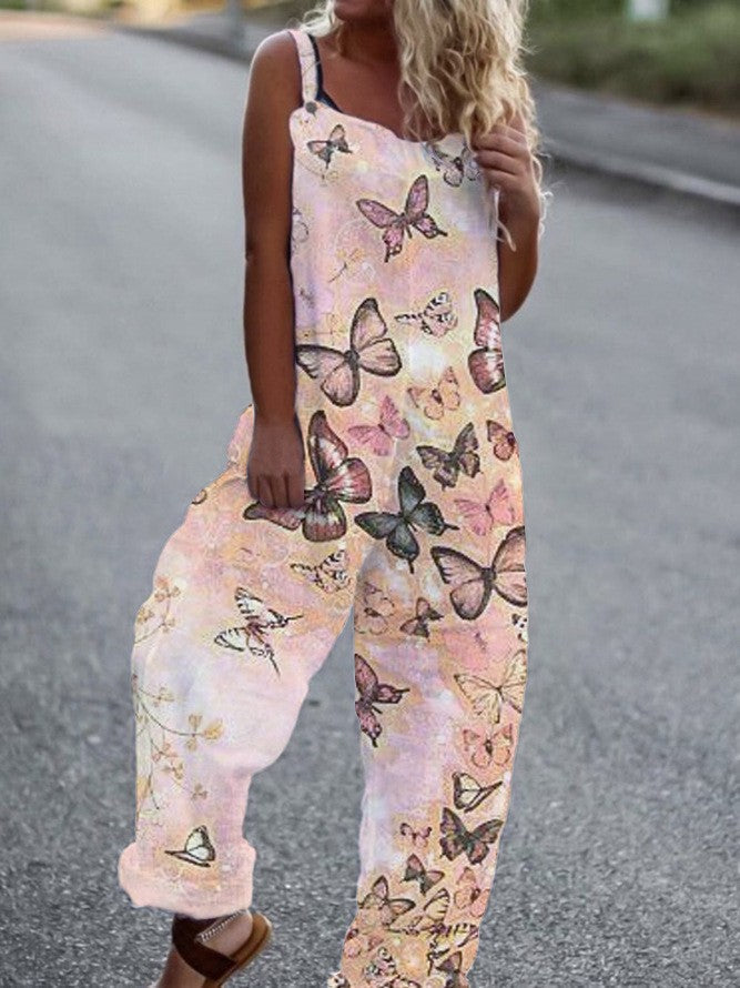 A woman wearing a loose-fitting, light pink sleeveless jumpsuit with an all-over multicolored butterfly print.