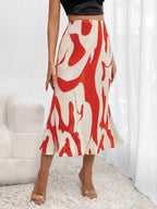 A person wears a cream and red pleated midi skirt with an abstract wavy pattern, paired with a black crop top.