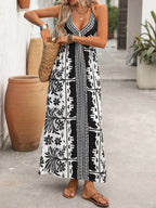 Women's printed halter neck maxi dress with tie-back detail, featuring vibrant floral pattern and flowing silhouette.