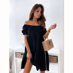 Woman wearing a black, off-the-shoulder, smocked mini dress with puff sleeves, carrying a small woven basket bag.