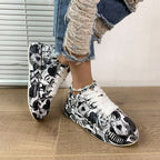 White lace-up sneakers featuring a black and white graphic playing card and heart print, worn with distressed jeans.