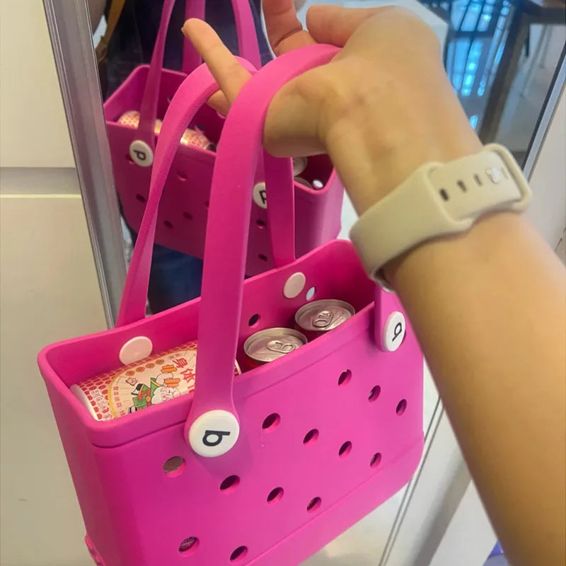 Hot pink waterproof EVA jelly beach tote with cutout details and white button accents, held in hand.